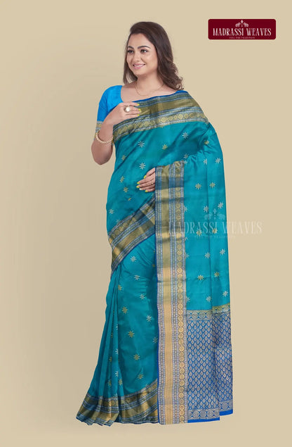 This exquisite Kanjeevaram Pure Silk Saree in blue is woven with intricate meena butta work and zari detailing, making it the perfect wedding saree. Crafted from pure silk, it is silk mark certified for authenticity. The attached blouse material allows for a customizable fit. Elevate your style and buy now.