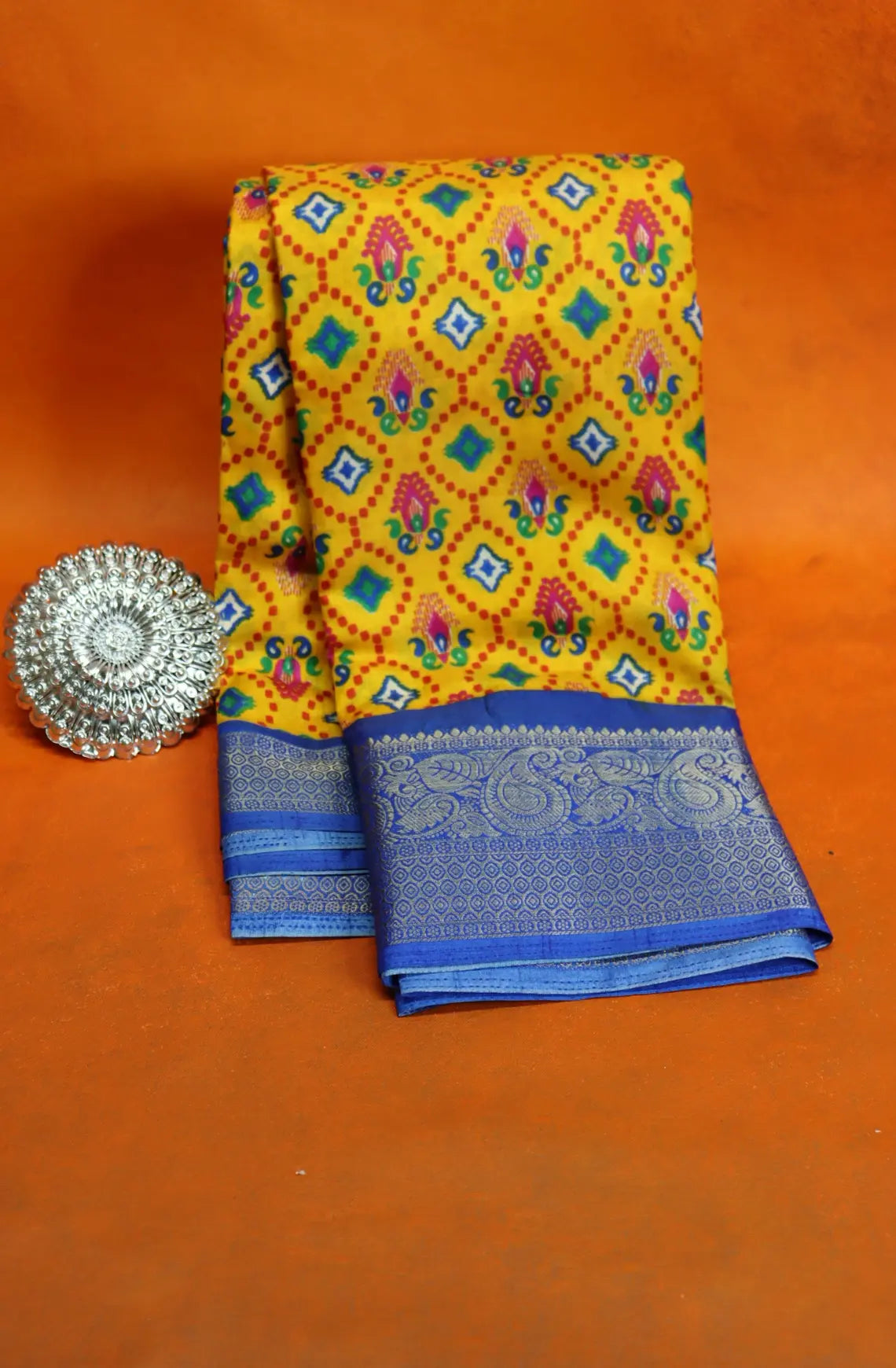 Elevate your style with our Patola Printed Saree! Made with fancy dola silk, it features a vibrant patola print and a stunning zari woven border. The rich mustard saree is accented with a maroon mango border, while the attached blouse material completes the ensemble. Available in six colours. Enjoy free shipping and an affordable price.